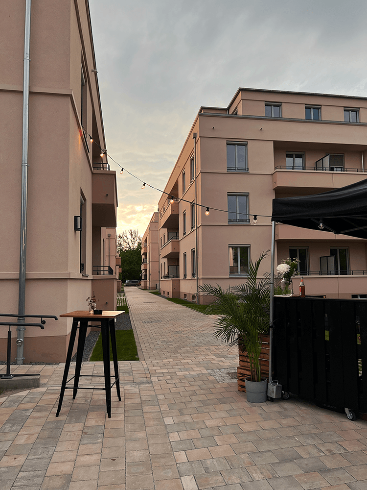 Moderne Wohnanlage mit Lichterketten im Außenbereich bei Sonnenuntergang, Deutschland.