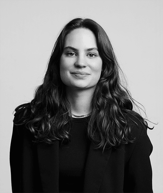 Eine Frau mit langen Haaren lächelt, Schwarz-Weiß-Porträt, neutraler Hintergrund. Maya Morin