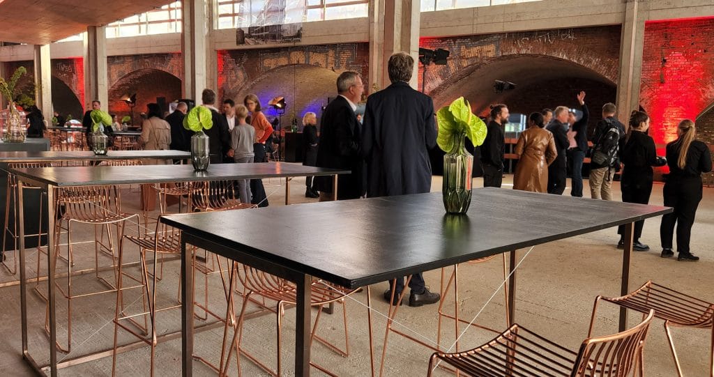 Moderne Veranstaltungshalle mit Tischen, Stühlen und Menschen bei einem Event oder Treffen.