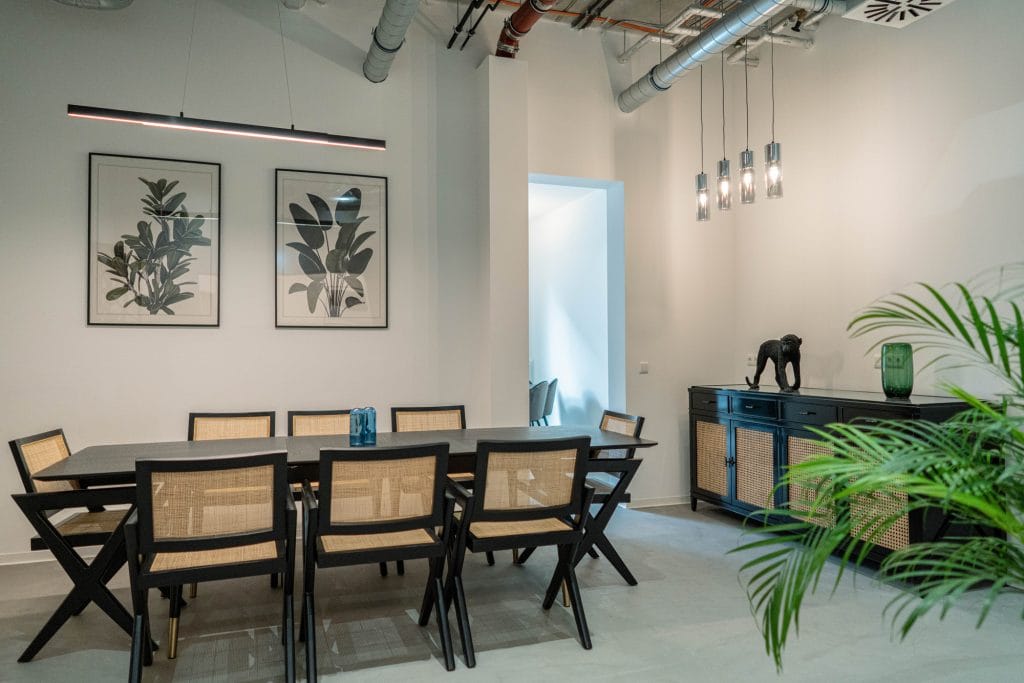 Moderner Essbereich mit Holzmöbeln, Pflanzen, zeitgenössischer Kunst und stilvoller Beleuchtung.
