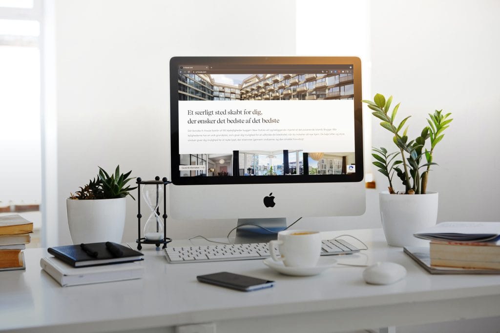 Moderner Schreibtisch mit Computer, Zimmerpflanzen und Tasse Kaffee in hellem Raum.