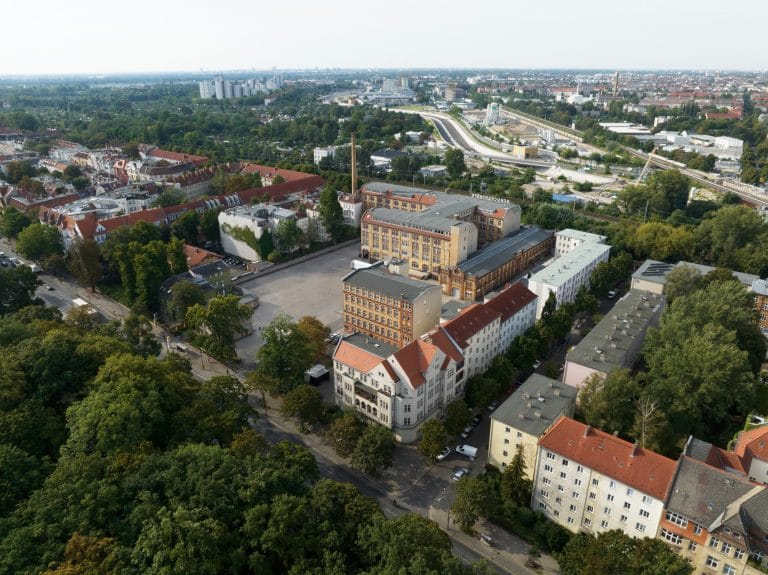 Luftaufnahme einer städtischen Gegend mit Gebäuden und viel Grünfläche in Berlin.