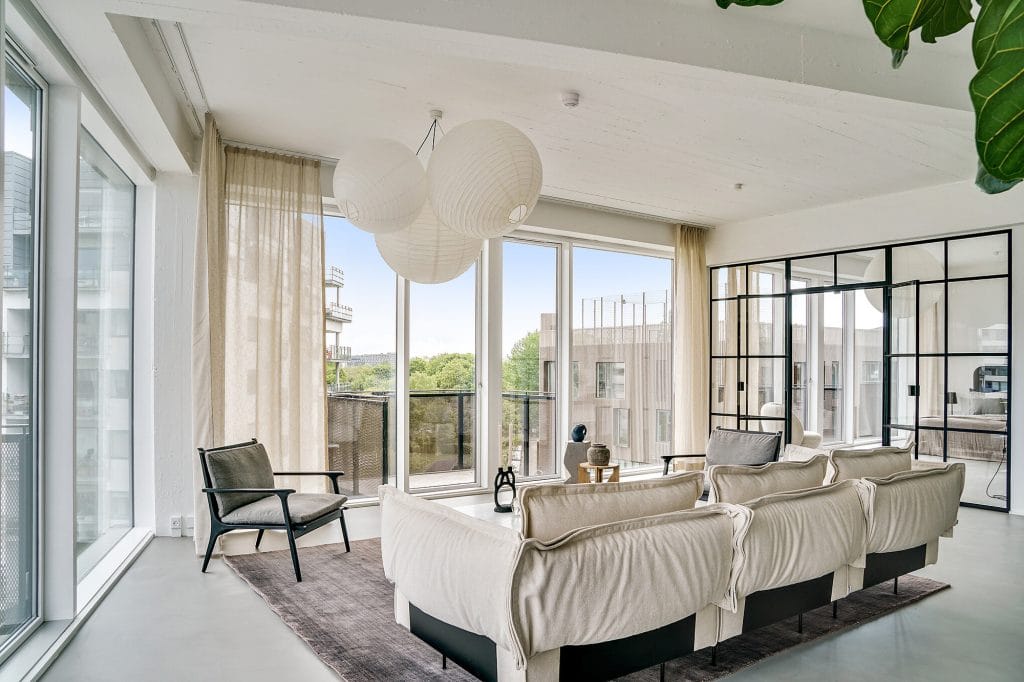 Moderne und helle Wohnzimmergestaltung mit großer Fensterfront und stilvoller Dekoration.