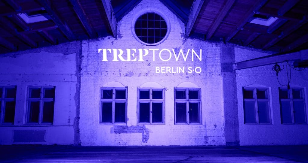 Alte Backsteinhalle mit blauem Licht und Beschriftung Treptown Berlin.