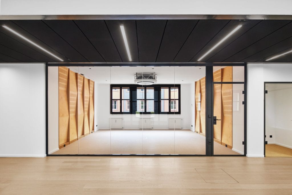 Modernes, leeres Büro mit Glaswänden, Holzelementen und großen Fenstern in minimalistischem Stil.