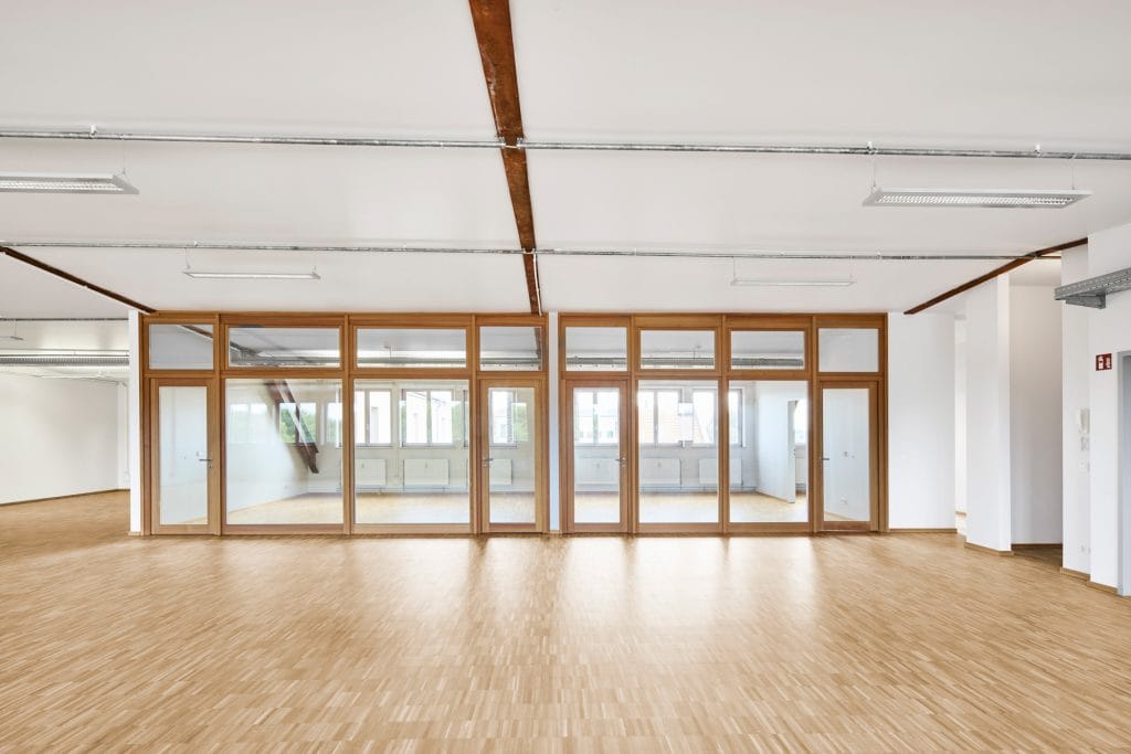 Großer, heller Büroraum mit Holzrahmenfenstern und modernem Design für vielseitige Nutzung.