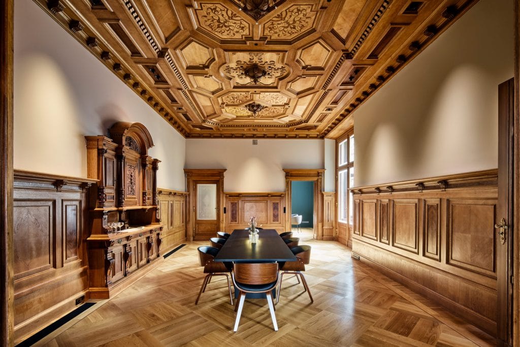 Historisches Besprechungszimmer mit Holzvertäfelung und kunstvoll dekorierter Decke.