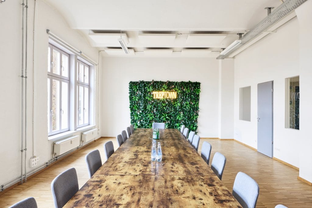 Moderner Konferenzraum mit Holztisch, Stühlen und vertikalem Garten an der Wand.