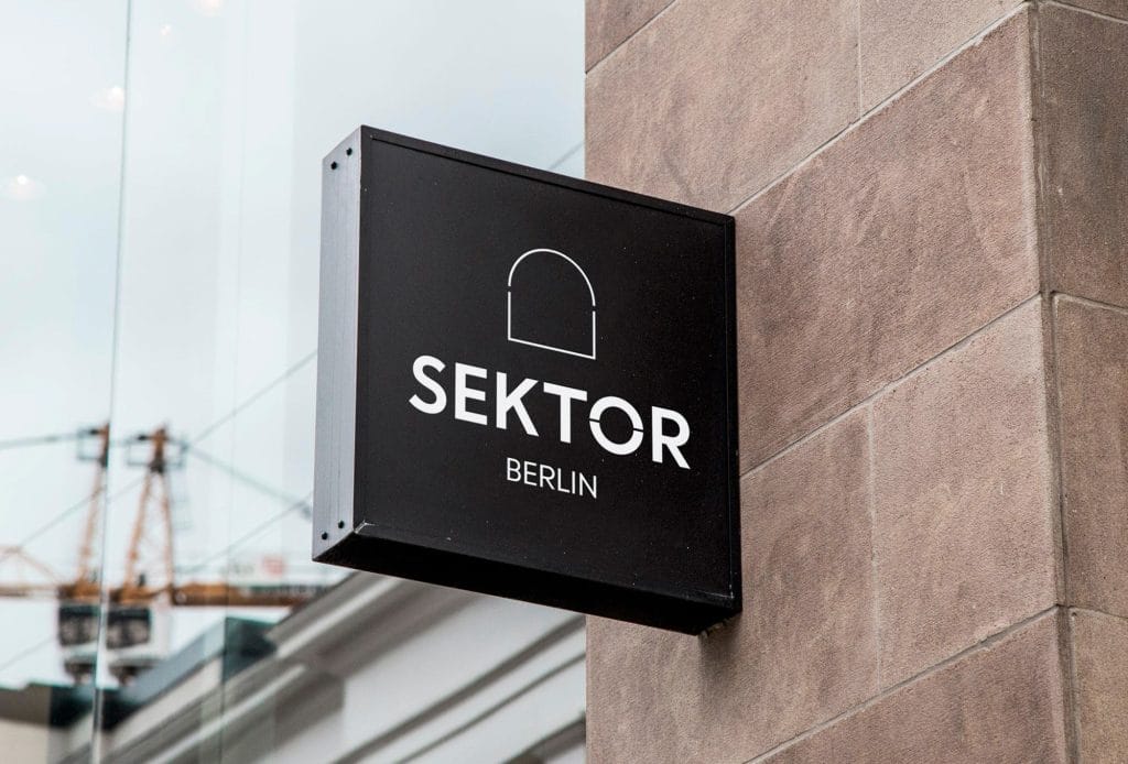 Schwarzes Schild mit der Aufschrift SEKTOR BERLIN an einer Gebäudeecke montiert.