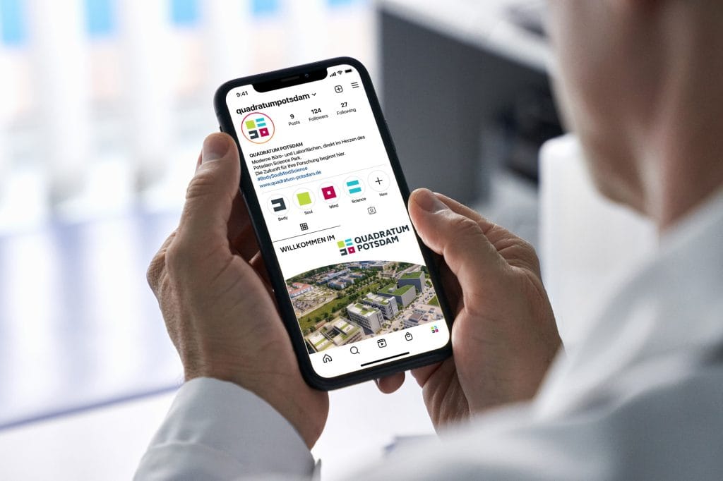 Person hält Smartphone mit Instagram-Seite von Quadratum Potsdam in der Hand.