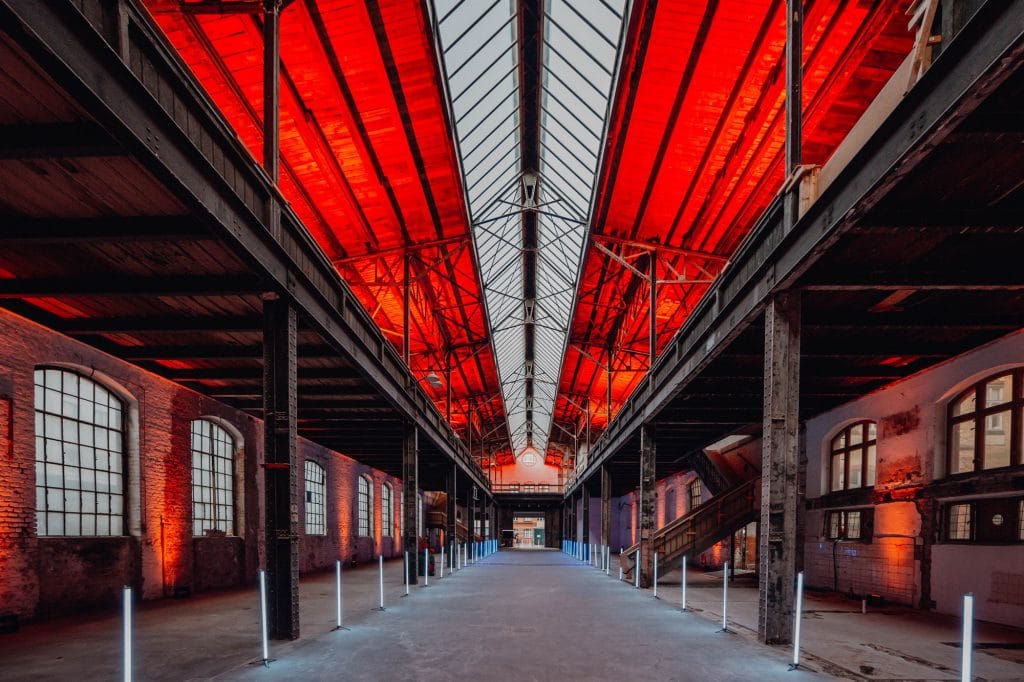 Industriehalle mit rotem Dach und symmetrischer Beleuchtung, architektonisches Design, Innenansicht.