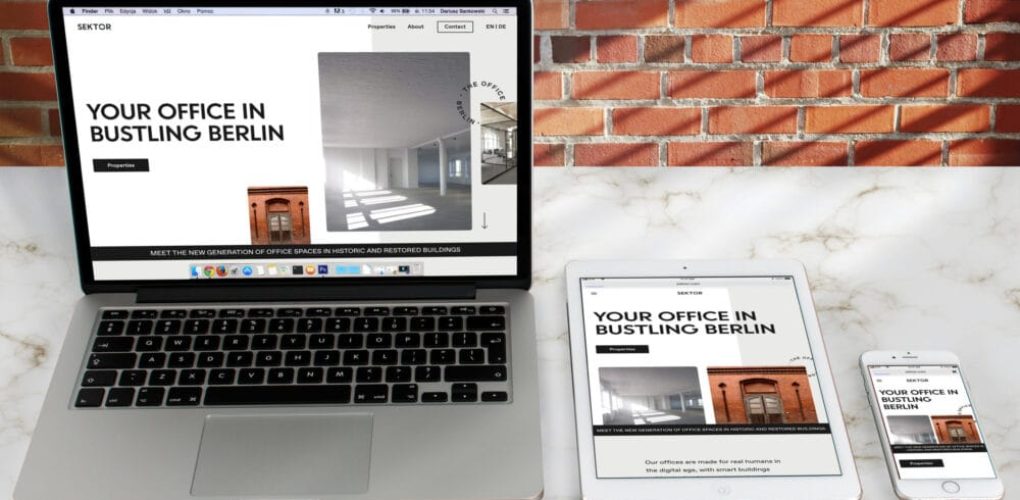 Laptop, Tablet und Smartphone zeigen Berliner Büro-Website mit roter Backsteinmauer im Hintergrund.