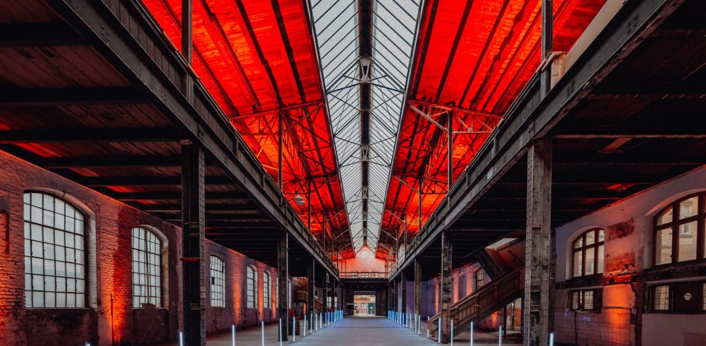 Industriehalle mit rotem Dach und symmetrischer Beleuchtung, architektonisches Design, Innenansicht.